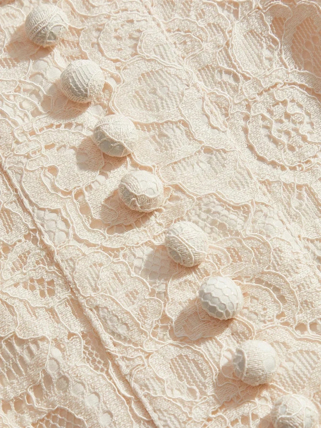 This exquisite cream lace dress features a delicate floral pattern and is adorned with unique, textured buttons, adding a.