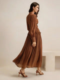 This elegant brown dress features a flowing maxi silhouette with delicate pleats and a fitted bodice, creating a.