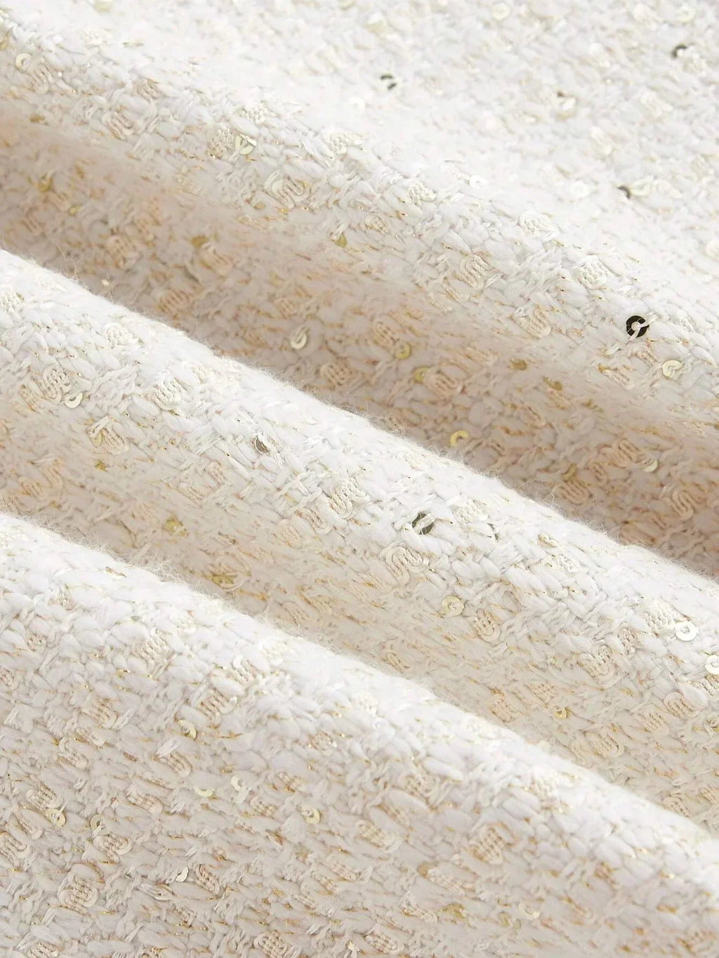 This elegant dress features a soft cream color with a textured, woven fabric that glimmers with subtle golden threads..