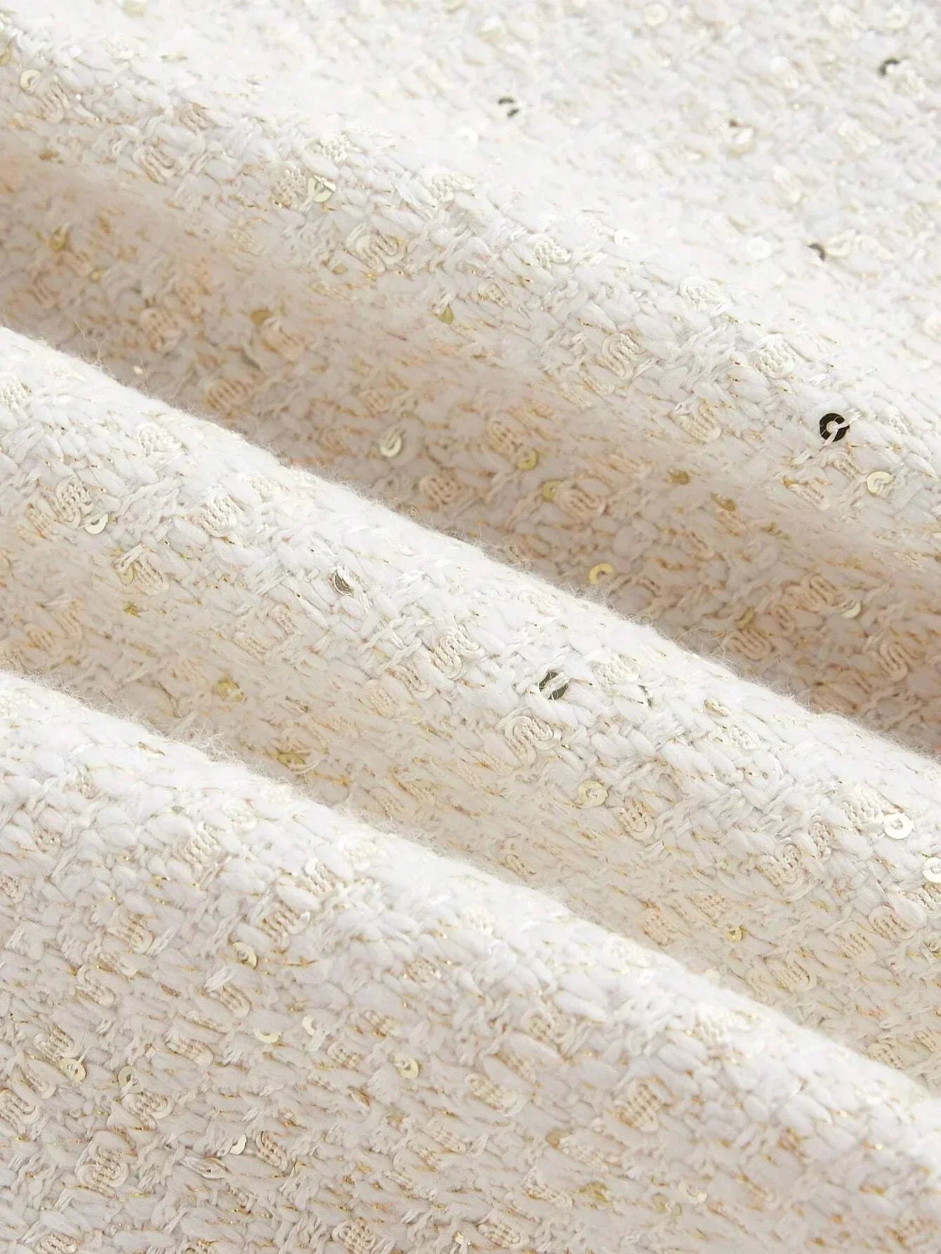 This elegant dress features a soft cream color with a textured, woven fabric that glimmers with subtle golden threads..