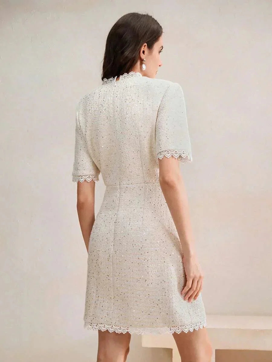 This elegant dress features a soft ivory hue with a textured fabric that adds dimension, while the delicate lace trim at the.