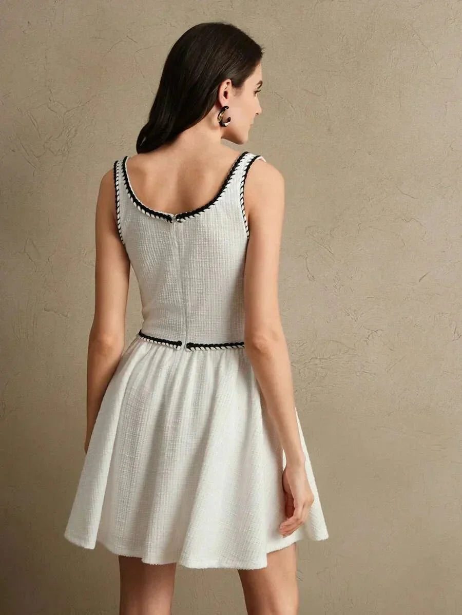 This delightful white dress features a flared skirt and a fitted bodice, accentuated by elegant black trim along the.