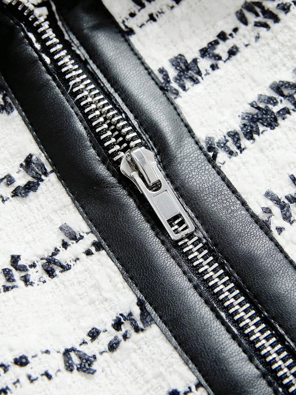 This stylish dress features a chic black and white design with intricate patterns, accentuated by a glossy black zipper that.