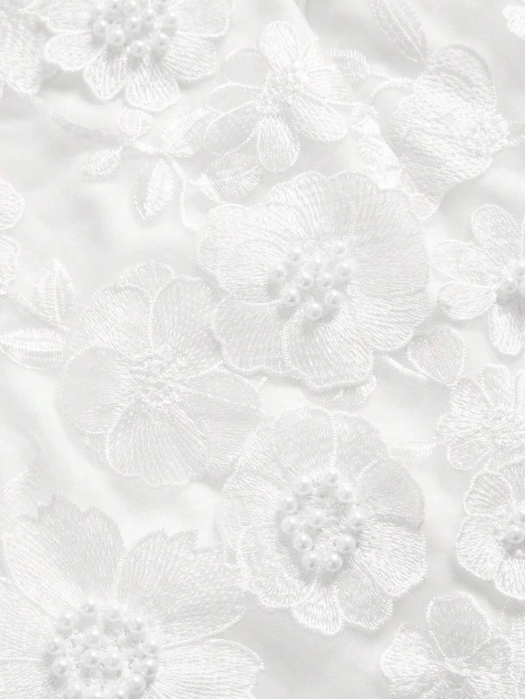Elegant white dress featuring intricate floral embroidery and delicate pearl accents, creating a romantic and feminine.