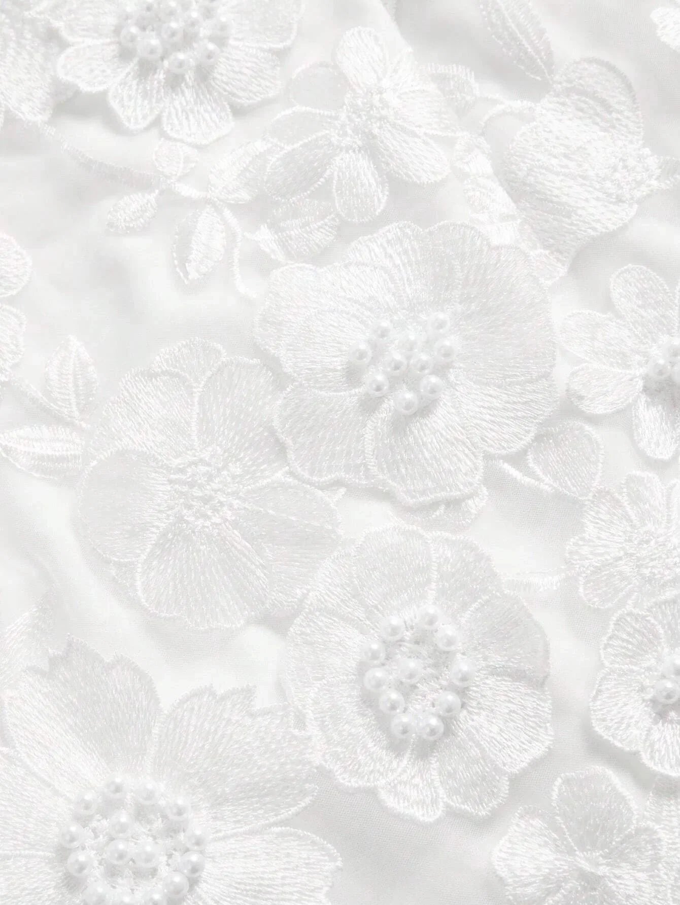 Elegant white dress featuring intricate floral embroidery and delicate pearl accents, creating a romantic and feminine.
