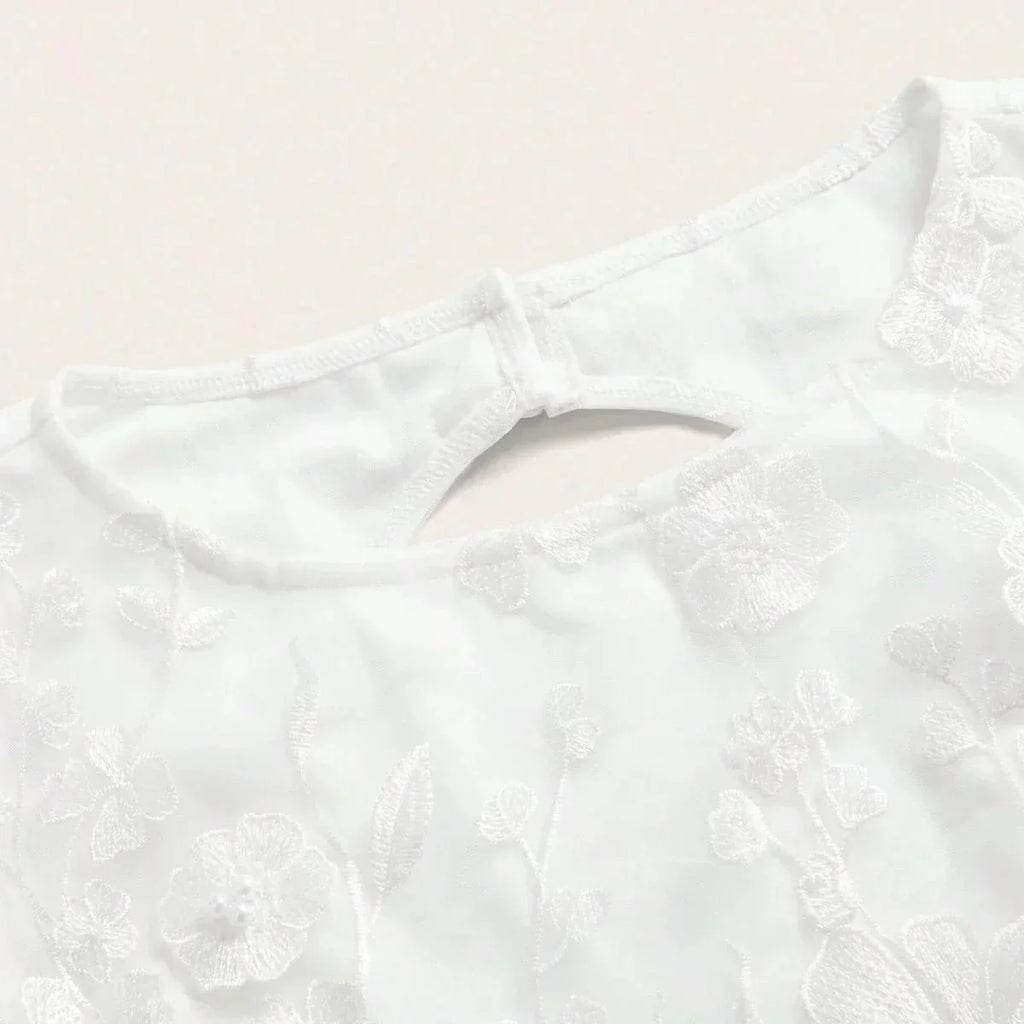 Delicate and chic, this white dress features intricate floral embroidery that adds a touch of elegance to its simple design..