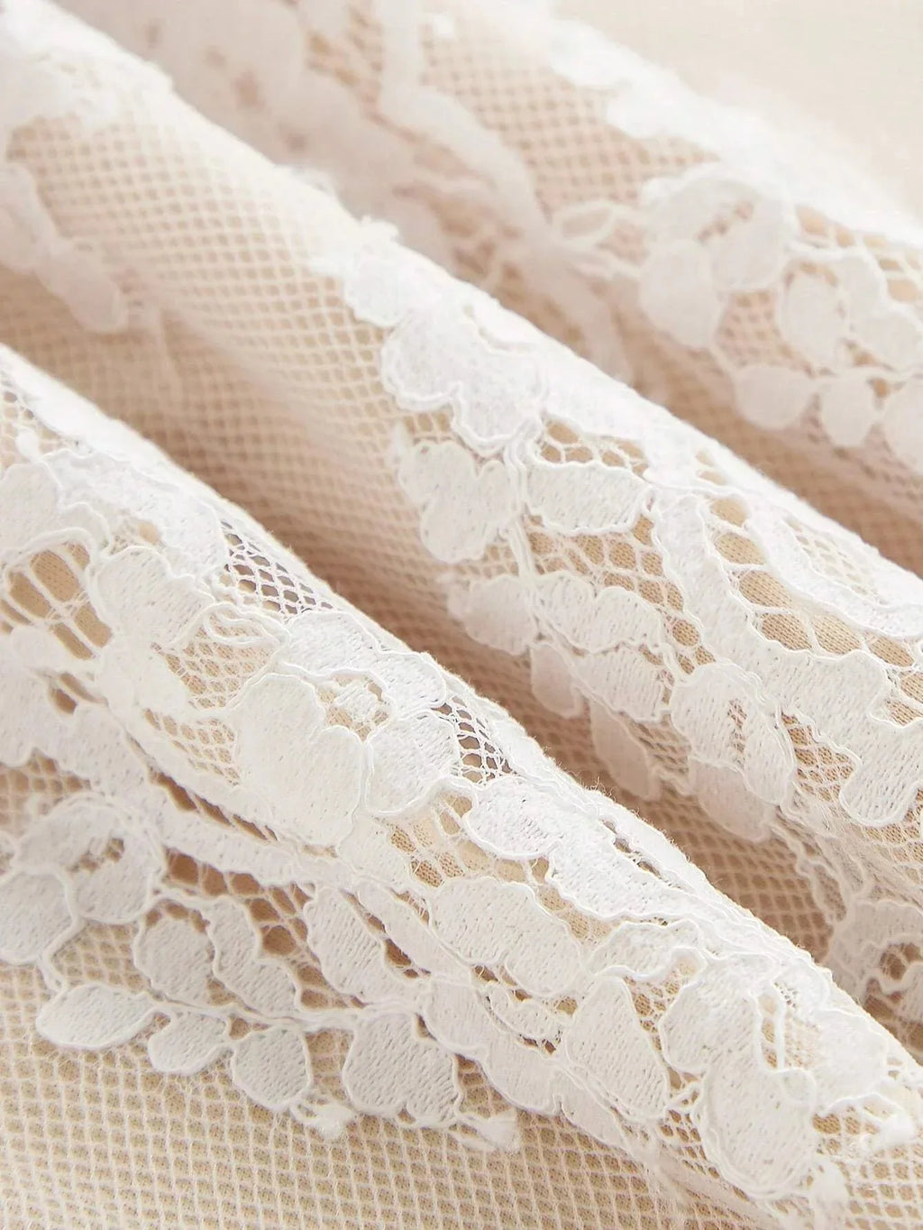 Delicate white lace features intricate floral patterns, lending a romantic touch to this elegant dress fabric. The.