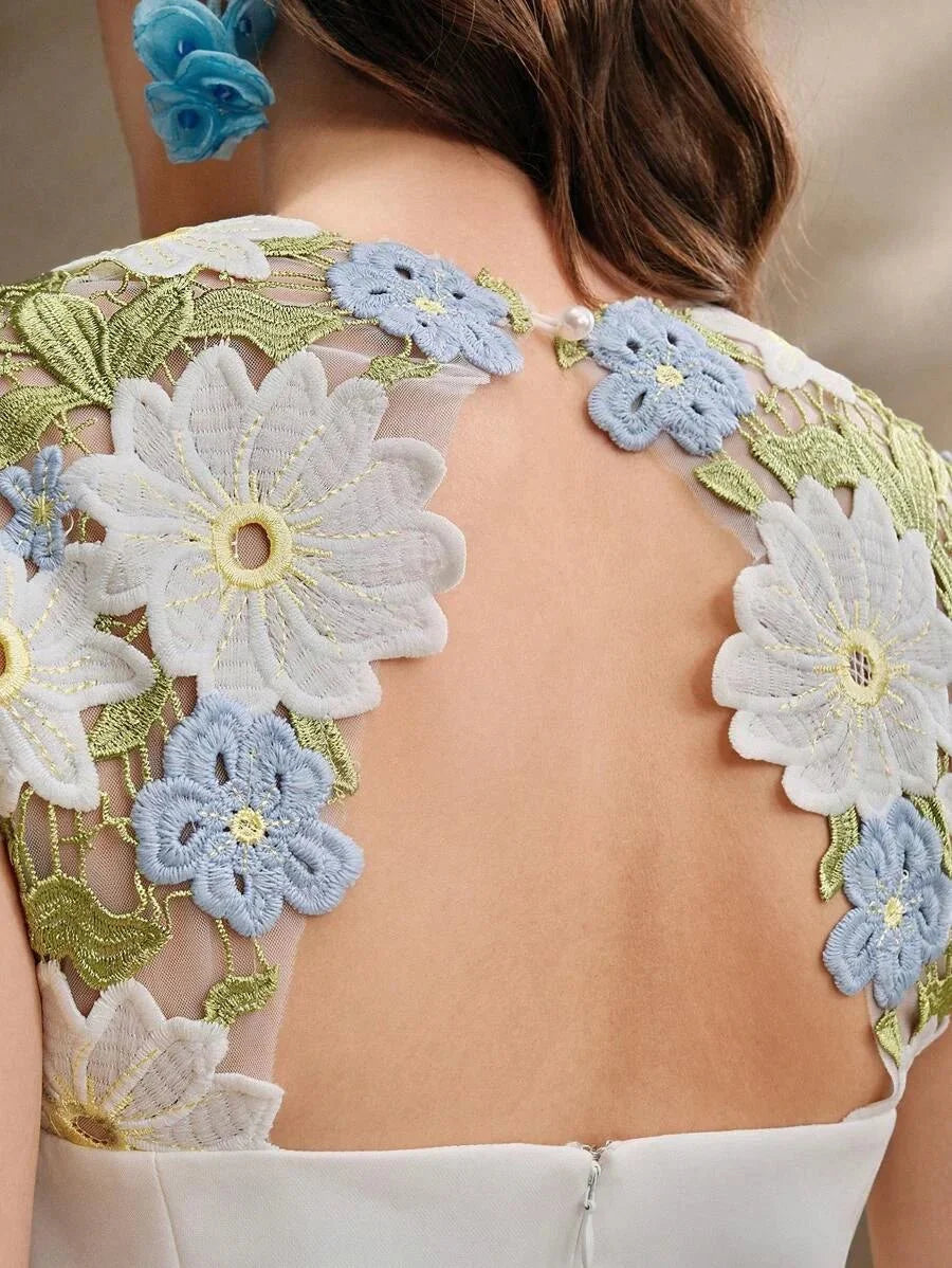 Delicate and charming, this dress features a stunning back adorned with intricate floral embroidery in soft shades of blue.