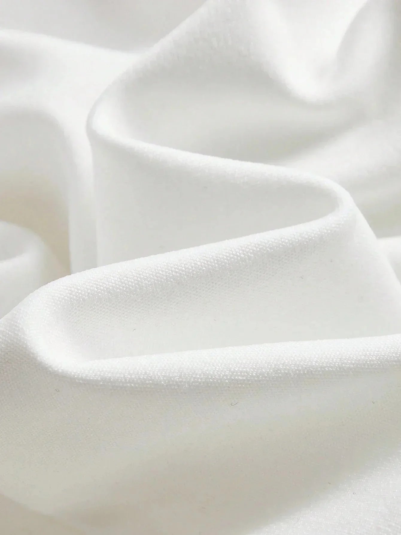 Luxuriously soft and elegantly draped, this pristine white fabric showcases a smooth texture reminiscent of delicate satin..