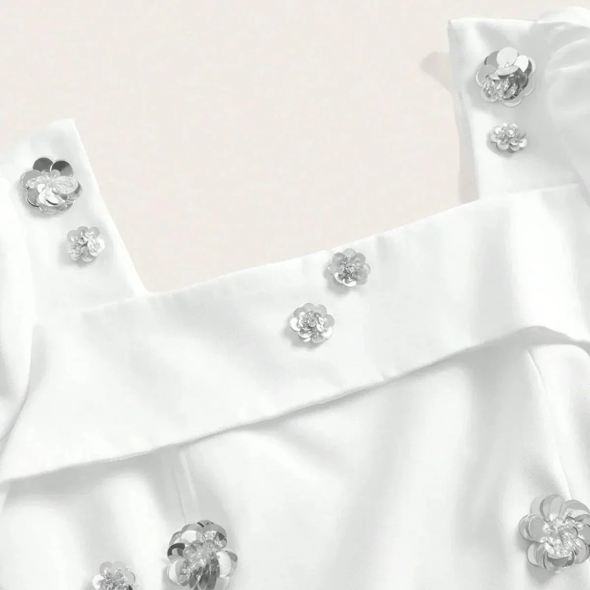 This elegant white dress features delicate silver flower embellishments that add a touch of glamour to its chic design. The.