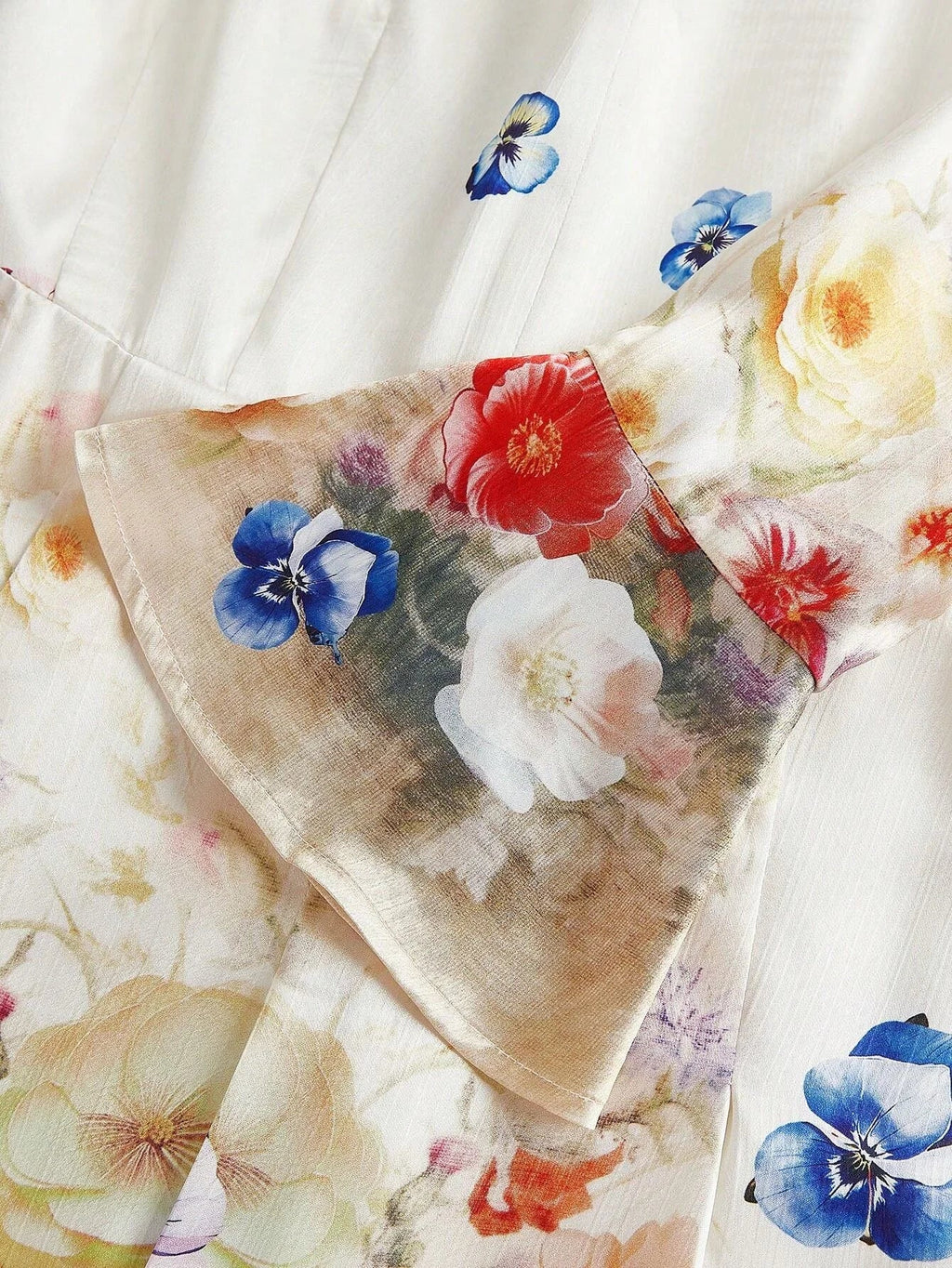 This stunning dress features a delicate floral pattern with vibrant hues of red, blue, and soft yellow blossoms against a.