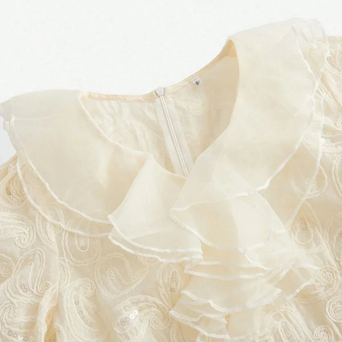 Delicate and ethereal, this cream-colored dress features a charming ruffled collar and intricate floral embroidery, giving.