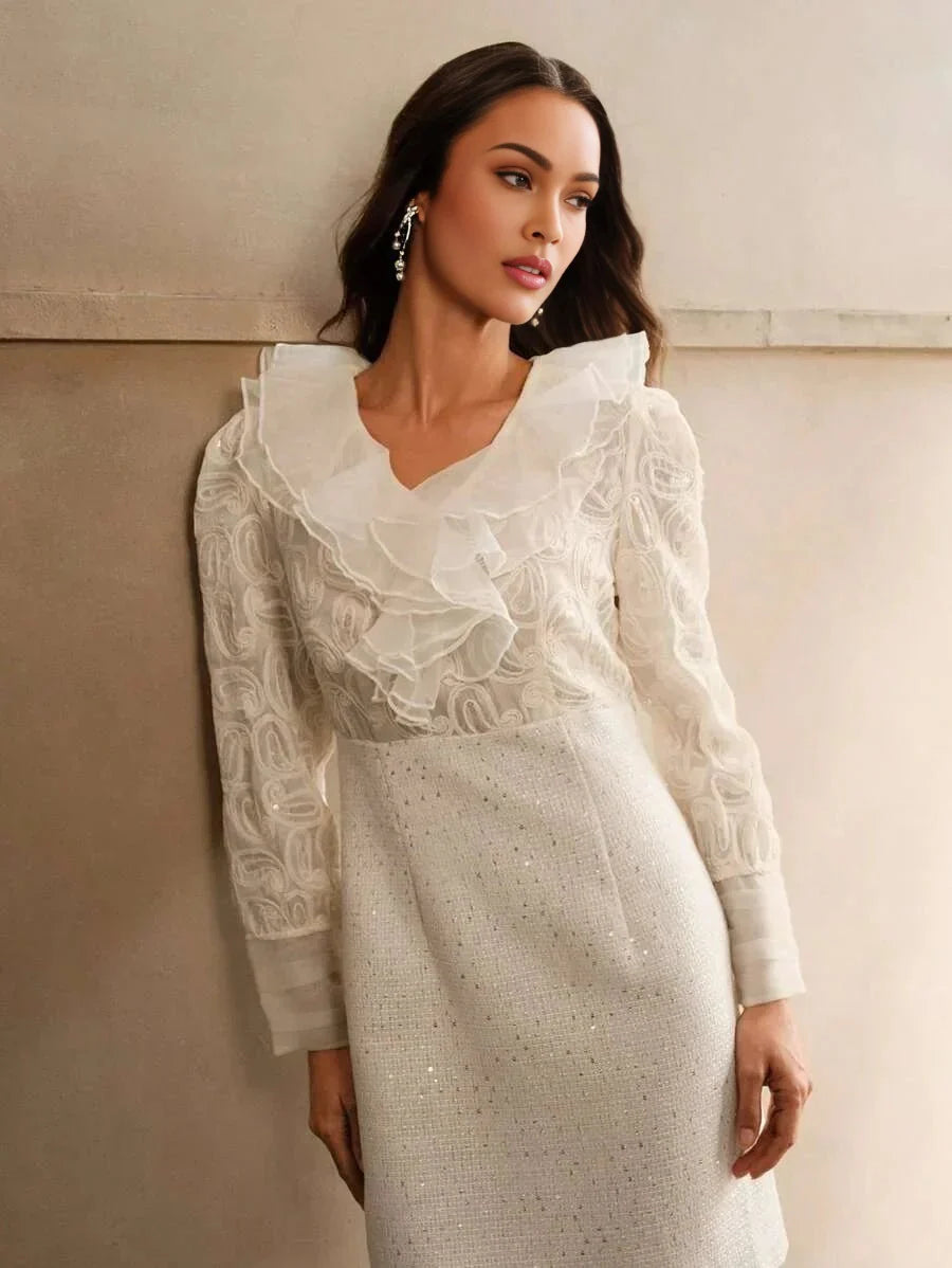 This elegant white dress features a delicate ruffled neckline and sheer, intricately patterned sleeves that exude a feminine.