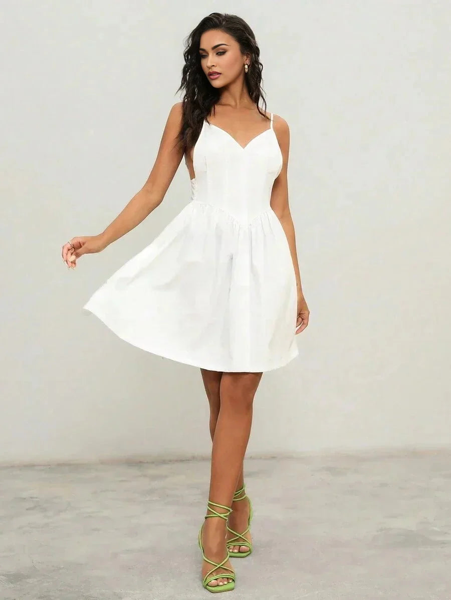 This charming white dress features a flattering A-line silhouette, complemented by delicate spaghetti straps and a deep.