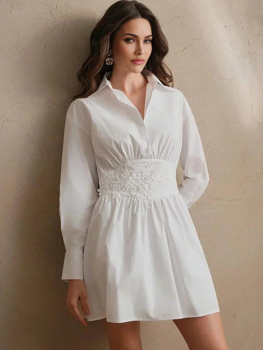 This charming white dress features a collared design with long sleeves, cinched at the waist with delicate floral embroidery.
