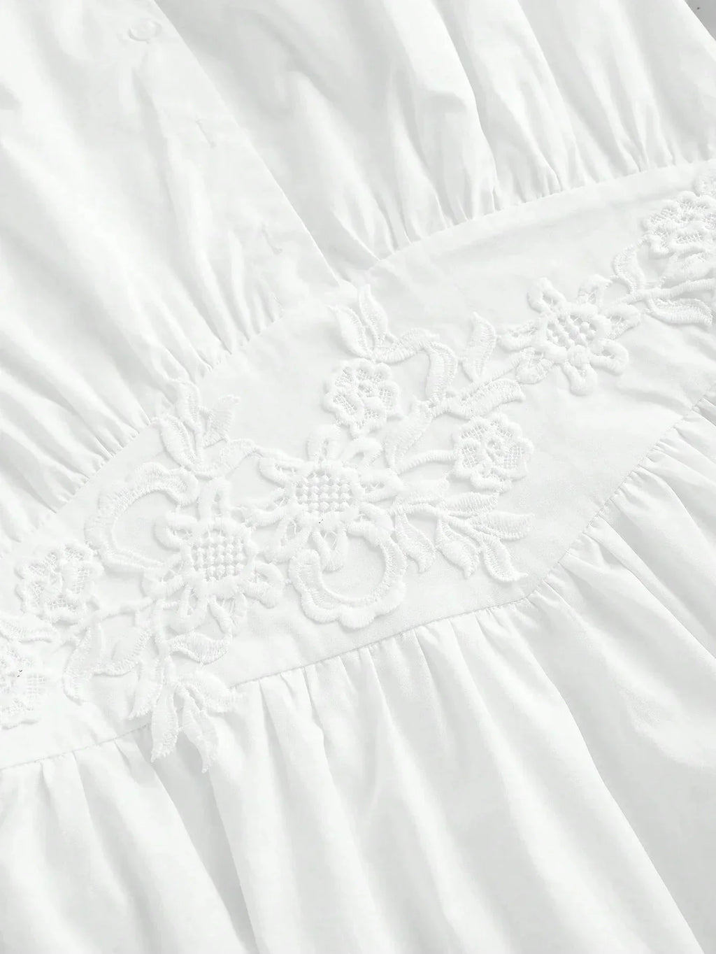 Charming and elegant, this white dress features delicate floral embroidery along the waistline, accentuating its soft,.