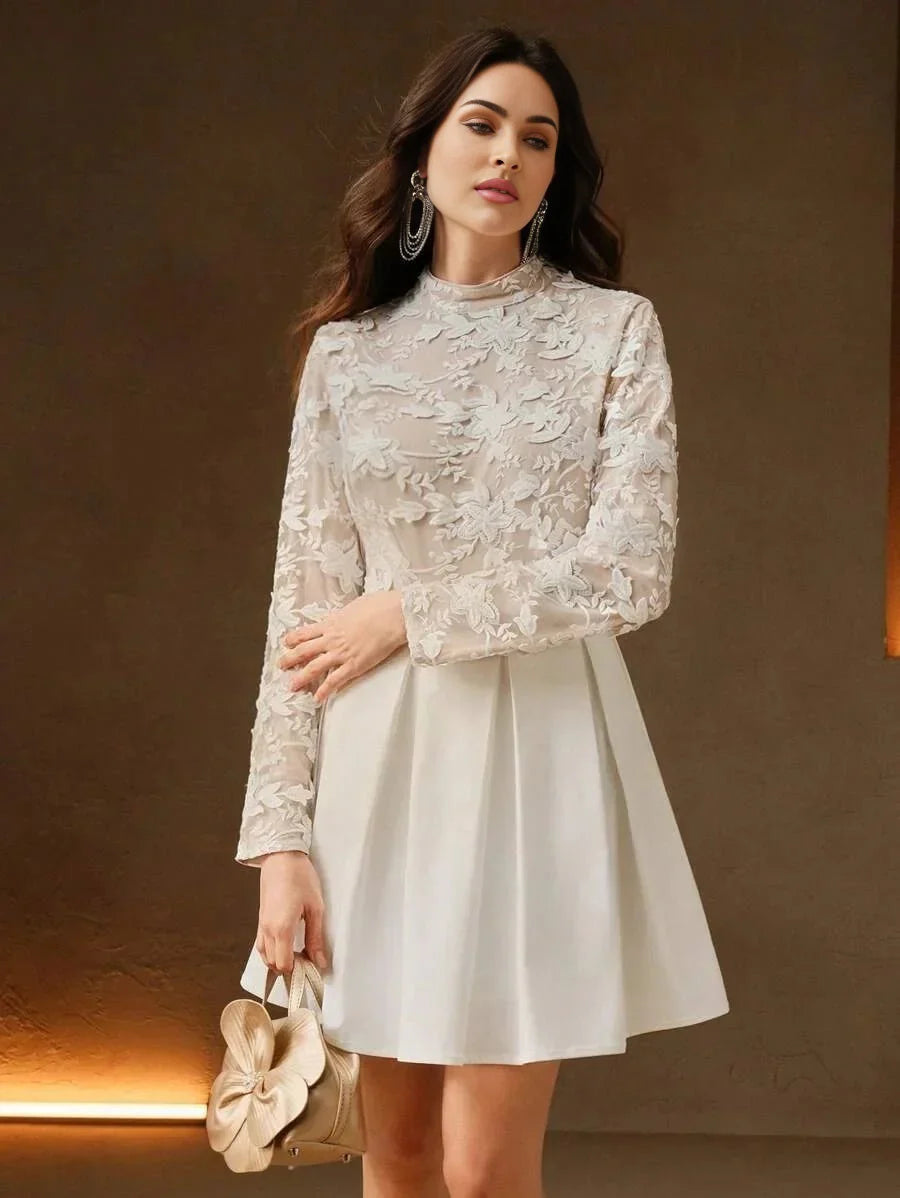 This elegant white dress features a delicate floral lace top with long sleeves and a high neckline, complemented by a flared.