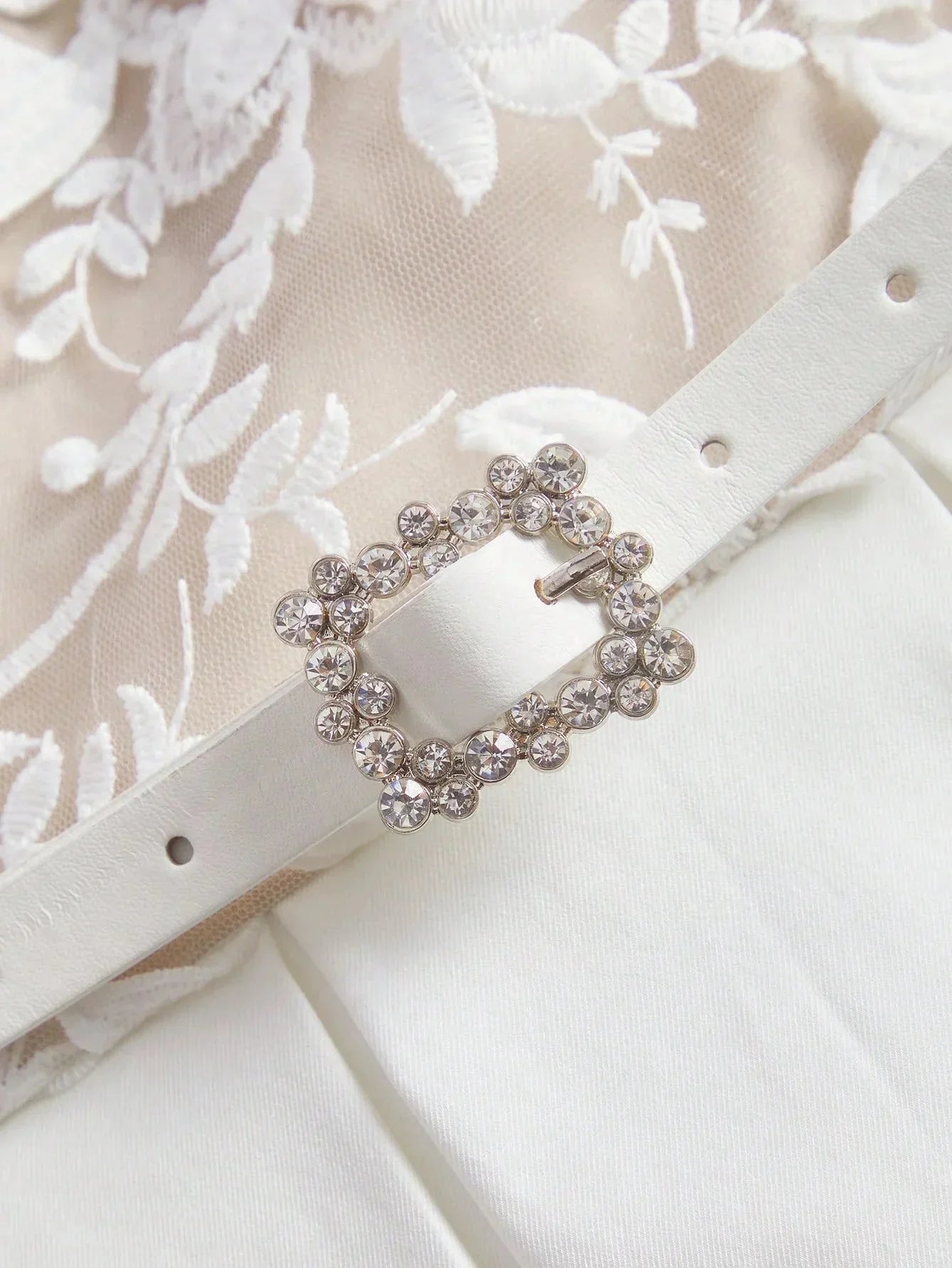 This elegant ivory dress features intricate floral embroidery on a delicate sheer overlay, complemented by a flattering.