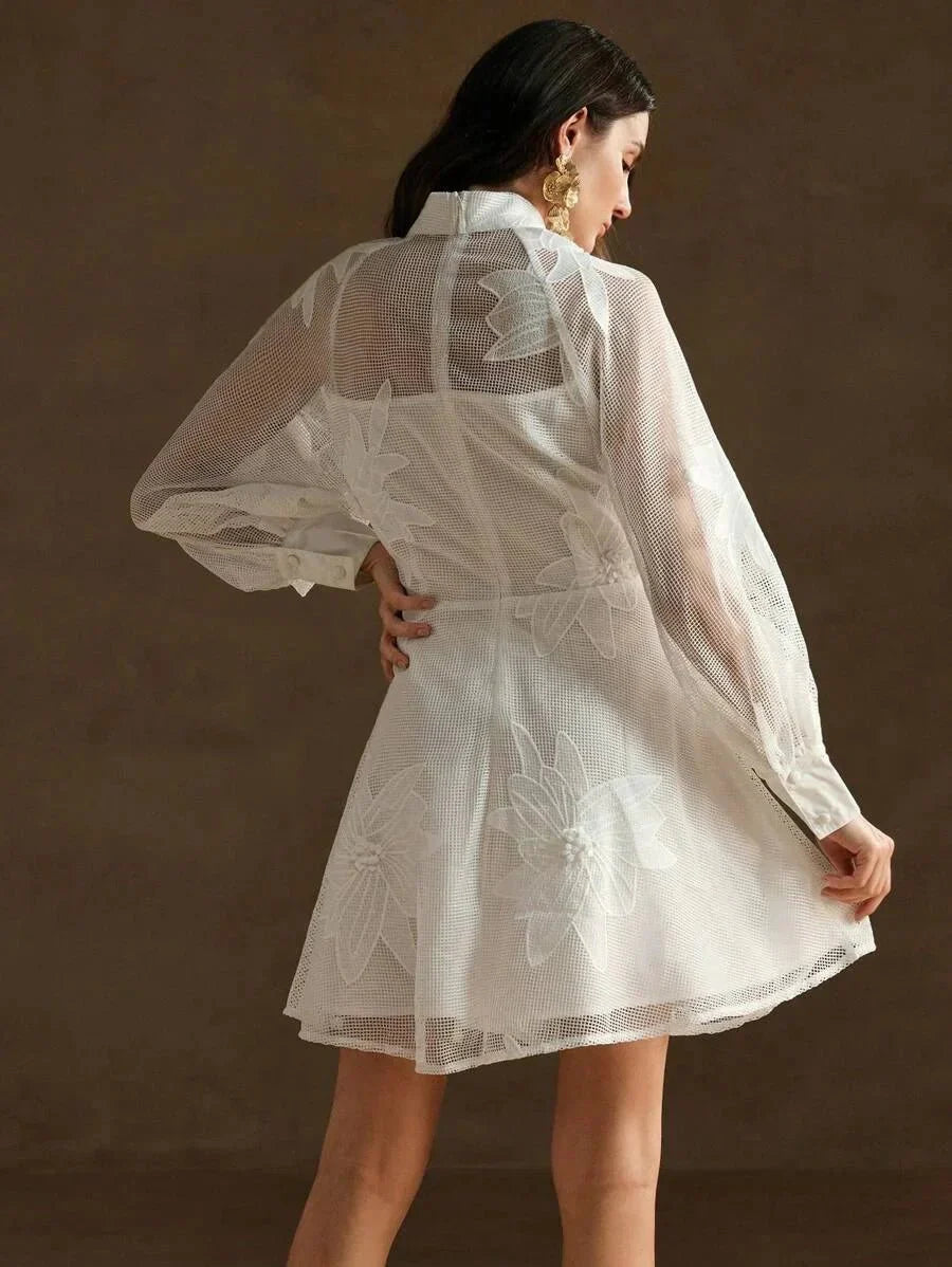 This enchanting white dress features a delicate sheer overlay with intricate floral embroidery, creating a lovely feminine.