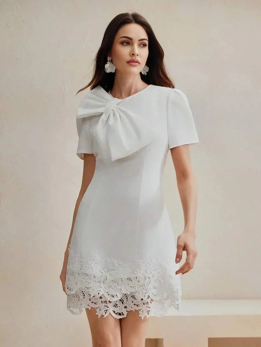 This elegant white dress features a chic bow detail at the neckline and short puff sleeves, designed for a flattering fit.