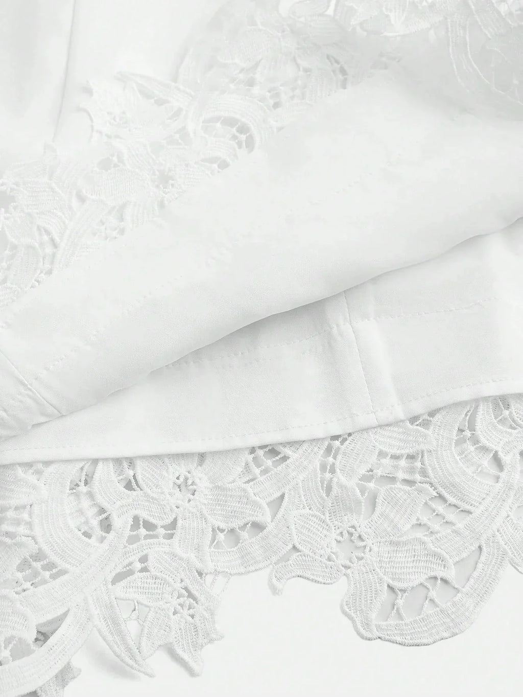 This elegant white dress features intricate floral lace detailing at the hem, adding a touch of sophistication to its.