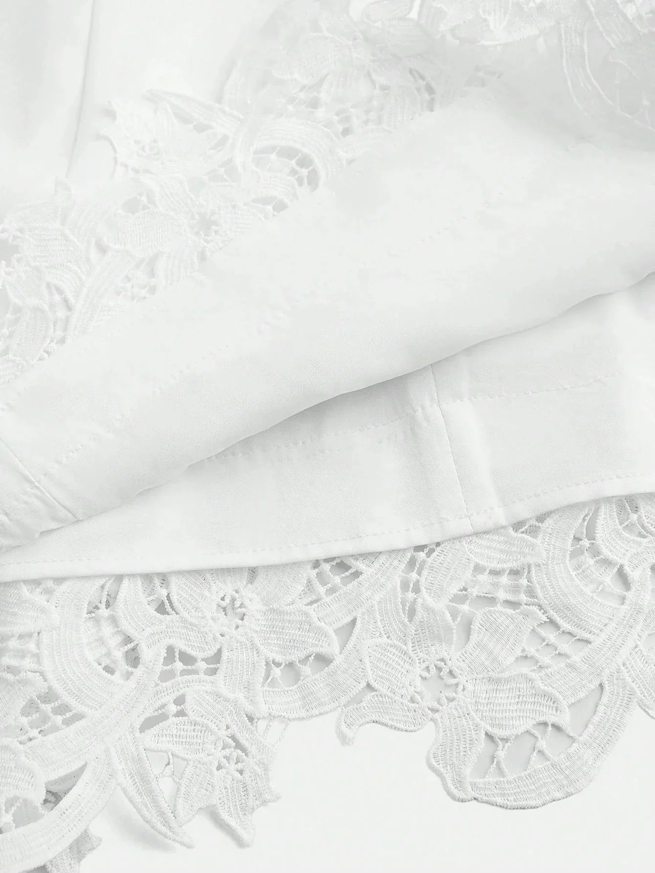 This elegant white dress features intricate floral lace detailing at the hem, adding a touch of sophistication to its.