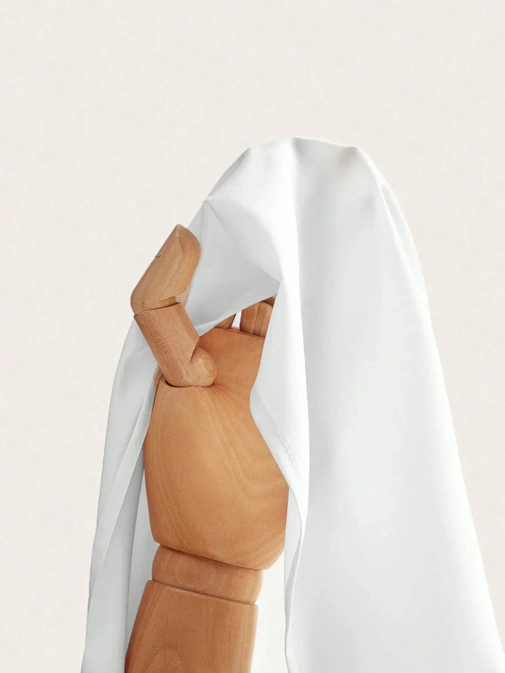 A flowing white dress drapes elegantly over a wooden mannequin, showcasing its soft fabric and relaxed fit. The lightweight.