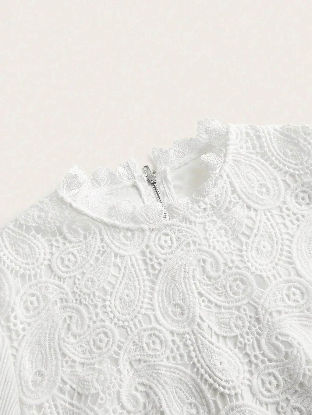 This elegant white dress features intricate lace detailing, showcasing a beautiful paisley pattern that adds a touch of.