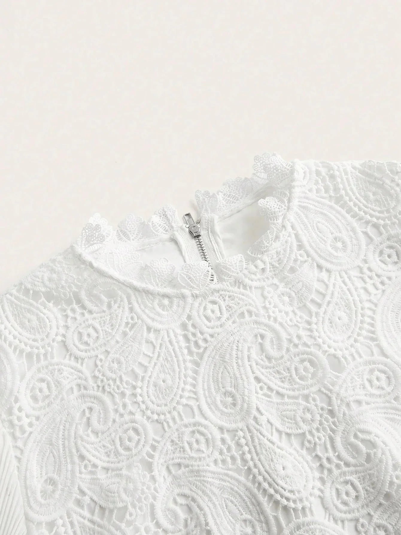 This elegant white dress features intricate lace detailing, showcasing a beautiful paisley pattern that adds a touch of.