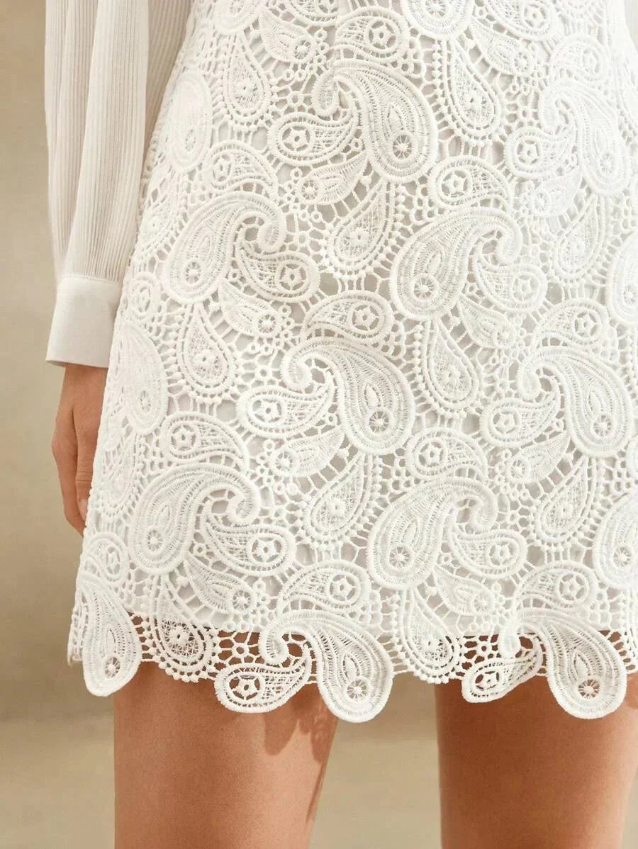 This elegant white dress features intricate lace detailing with a delicate paisley pattern, creating a romantic and timeless.