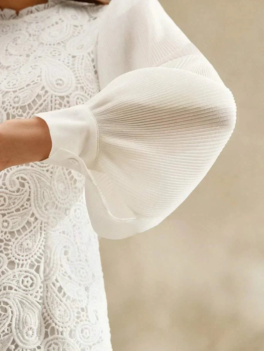 This elegant white dress features intricate lace detailing and soft pleated puff sleeves that create a romantic silhouette..