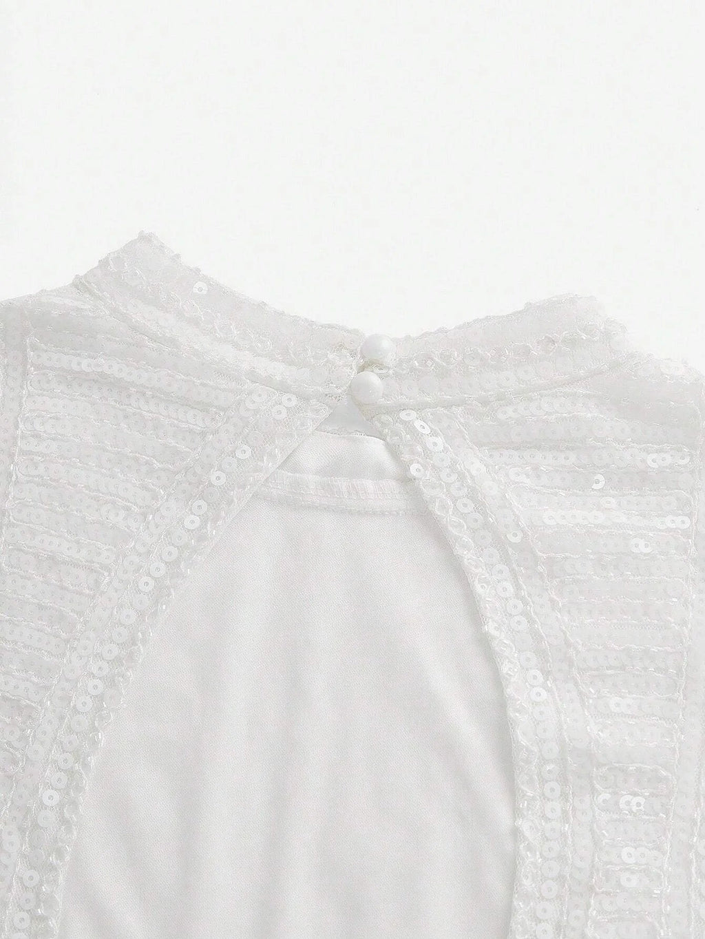 This elegant white dress features a delicate, sequined bodice that shimmers softly in the light, complemented by a smooth.