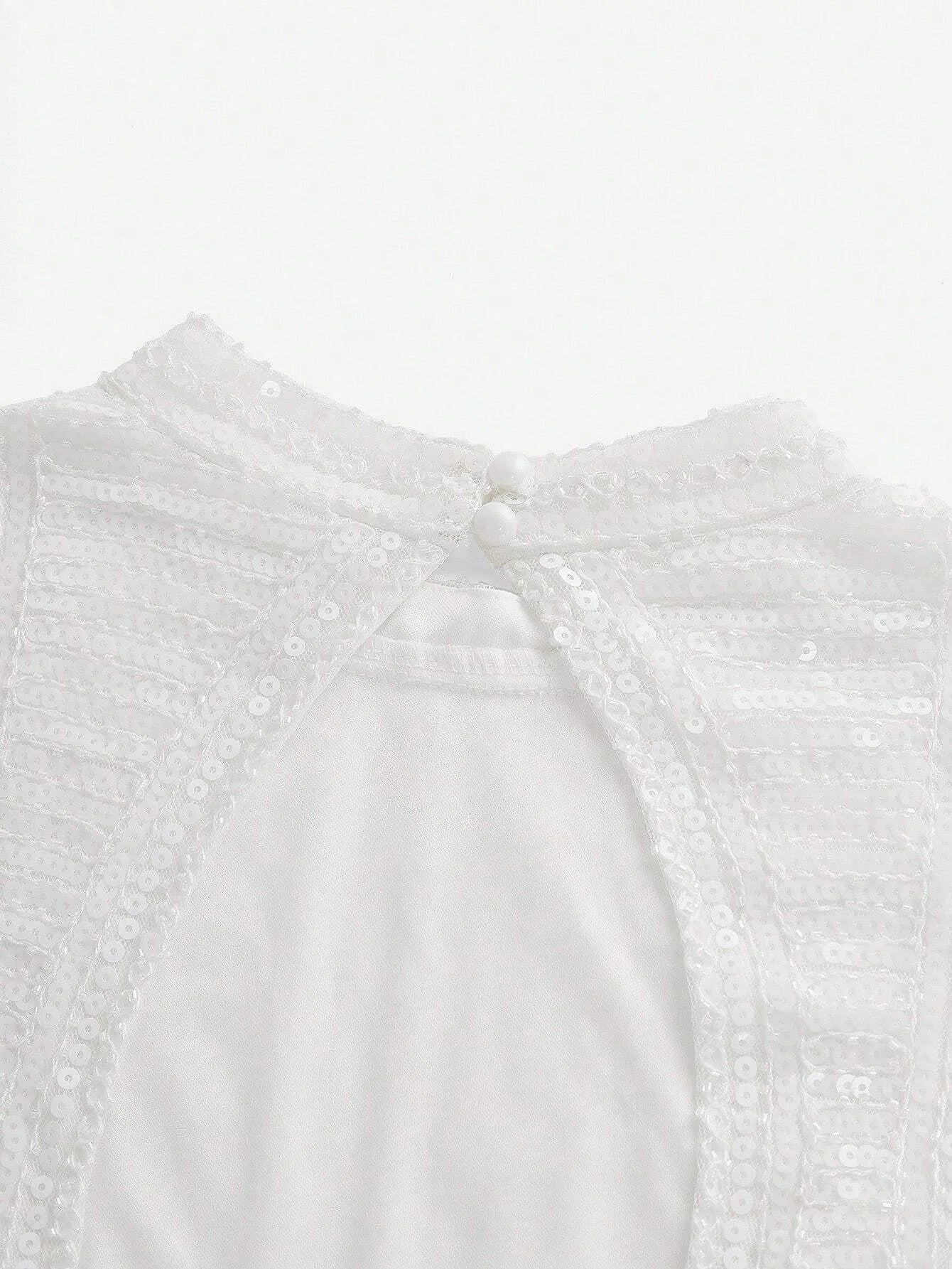 This elegant white dress features a delicate, sequined bodice that shimmers softly in the light, complemented by a smooth.