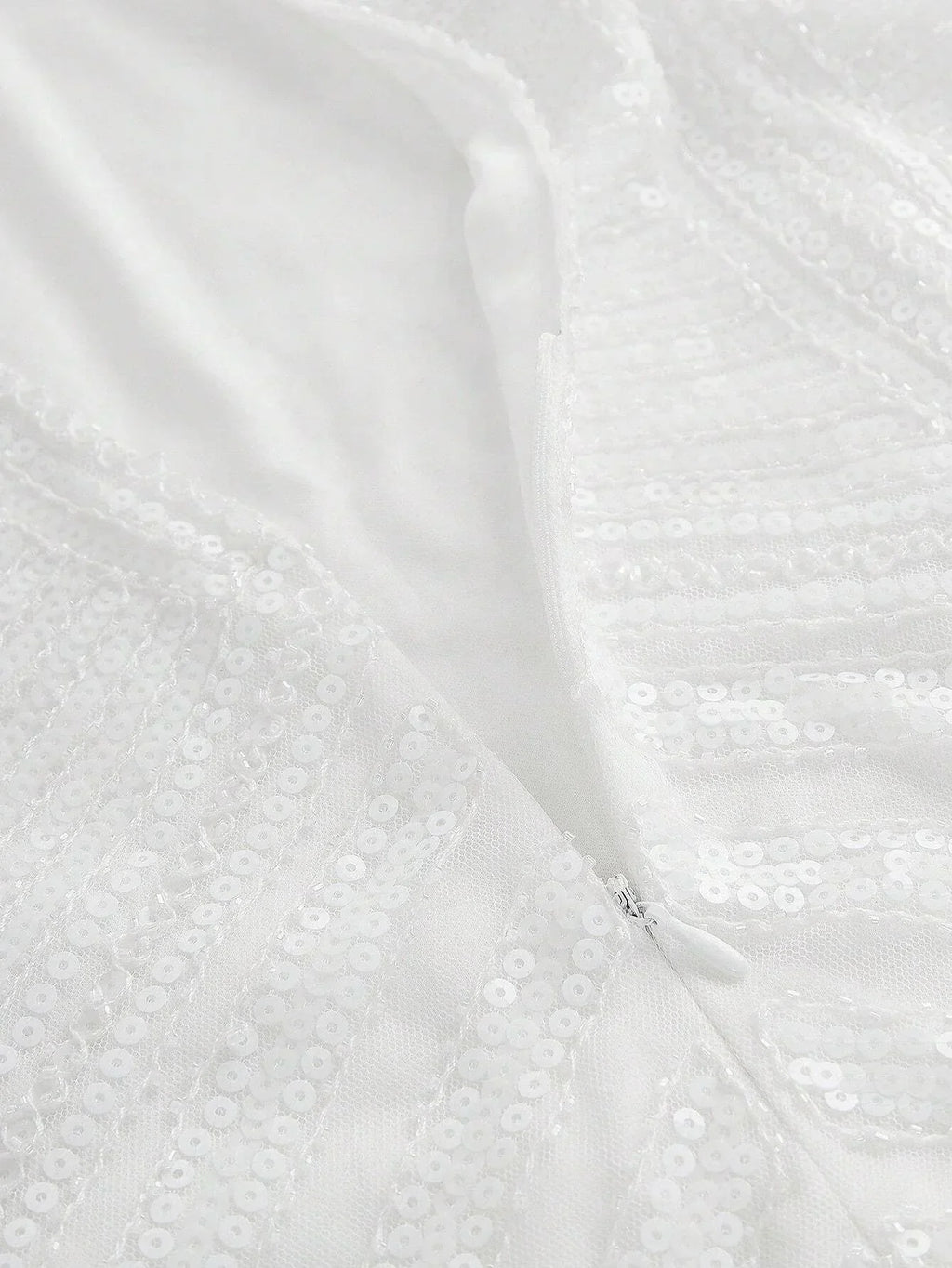 This elegant white dress features a shimmering sequin design that catches the light beautifully, offering a glamorous touch.