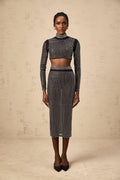 Woman wearing a black twopiece outfit consisting of a rhinestoneembellished mesh top and matching skirt